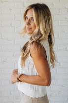 Blonde woman wearing a cream vest with scallop trim and floral embroidery.