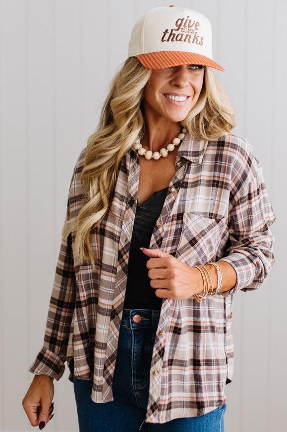 Blonde woman in a bright studio wearing dark jeans and a hat with a Taupe Oversized Flannel Shirt over a charcoal grey tank.