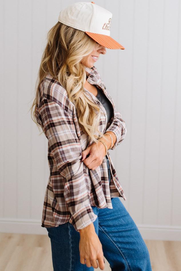 Blonde woman in a bright studio wearing dark jeans and a hat with a Taupe Oversized Flannel Shirt over a charcoal grey tank.