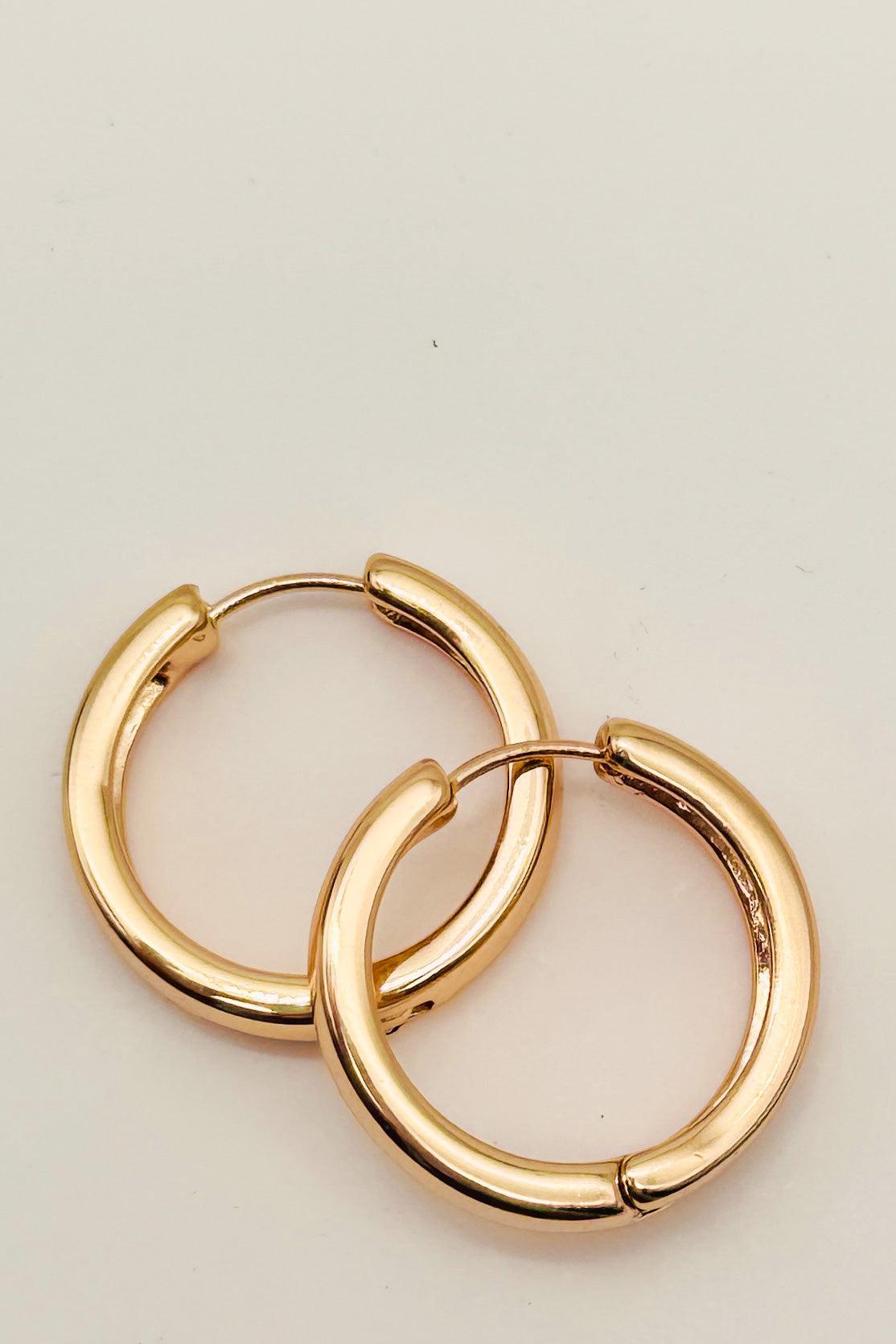Gold hoop earrings on a light beige background