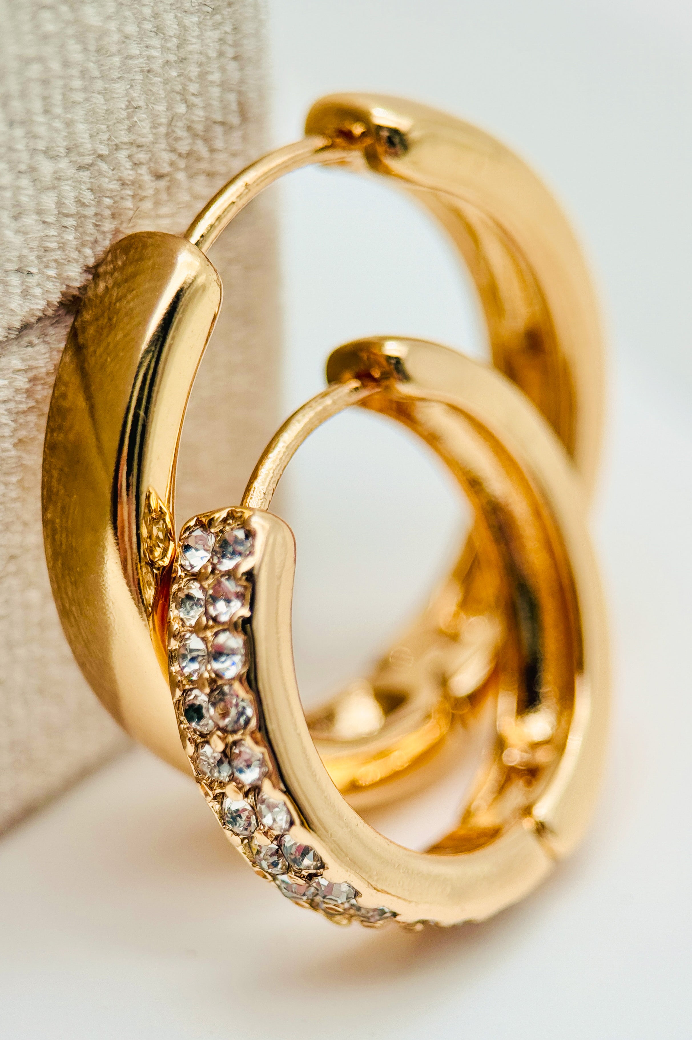 Gold hoop earrings with embedded crystals on a light background
