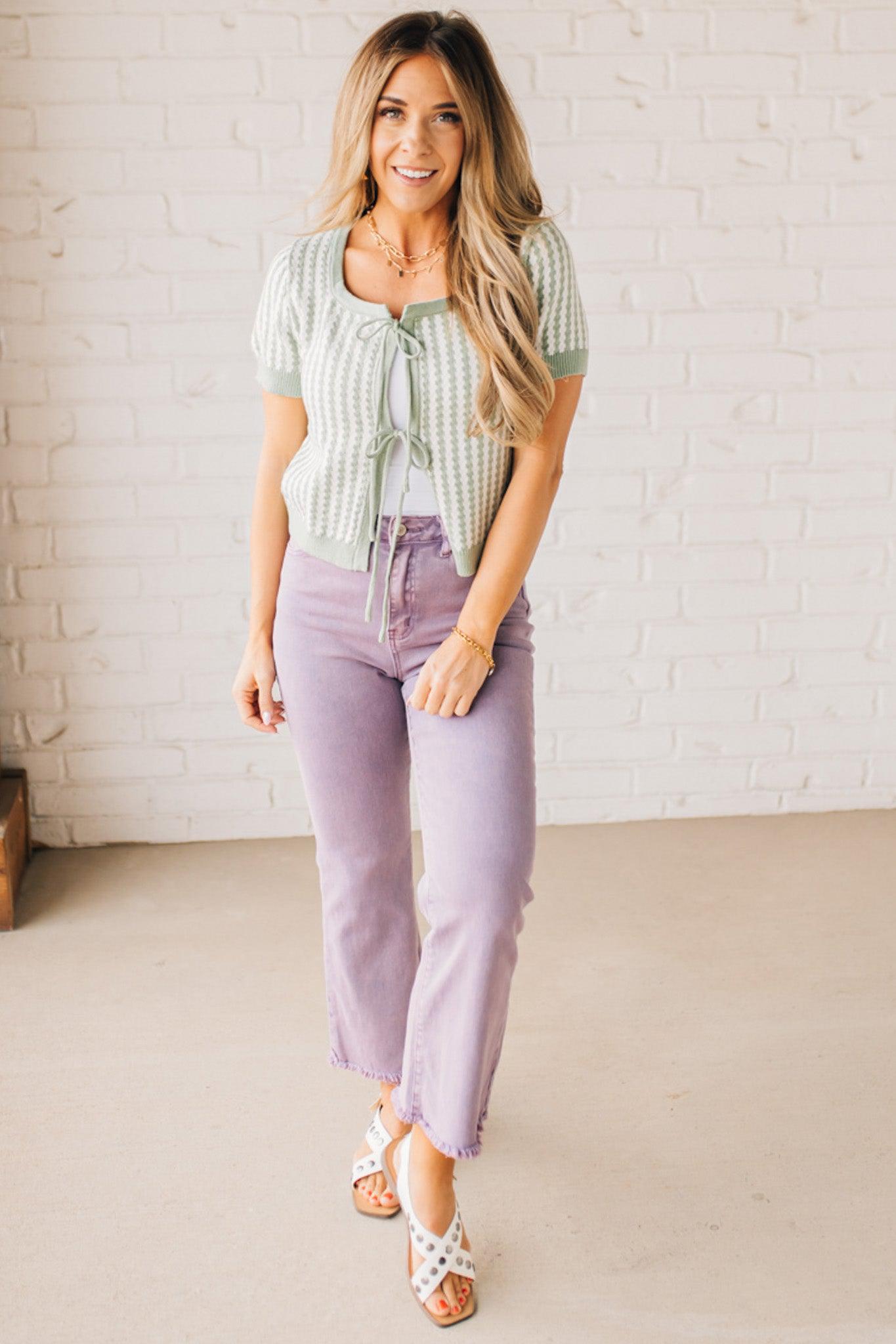 BLONDE WOMAN IN PURPLE PANTS WEARING A LIGHT GREEN AND WHITE TIE FRONT TEXTURED VERTICAL STRIPE SCOOP NECK KNIT SWEATER WITH DOUBLE TIES.