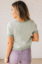 BLONDE WOMAN IN PURPLE PANTS WEARING A LIGHT GREEN AND WHITE TIE FRONT TEXTURED VERTICAL STRIPE SCOOP NECK KNIT SWEATER WITH DOUBLE TIES.