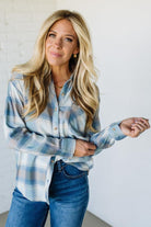 Woman wearing a blue plaid shirt and jeans against a white background