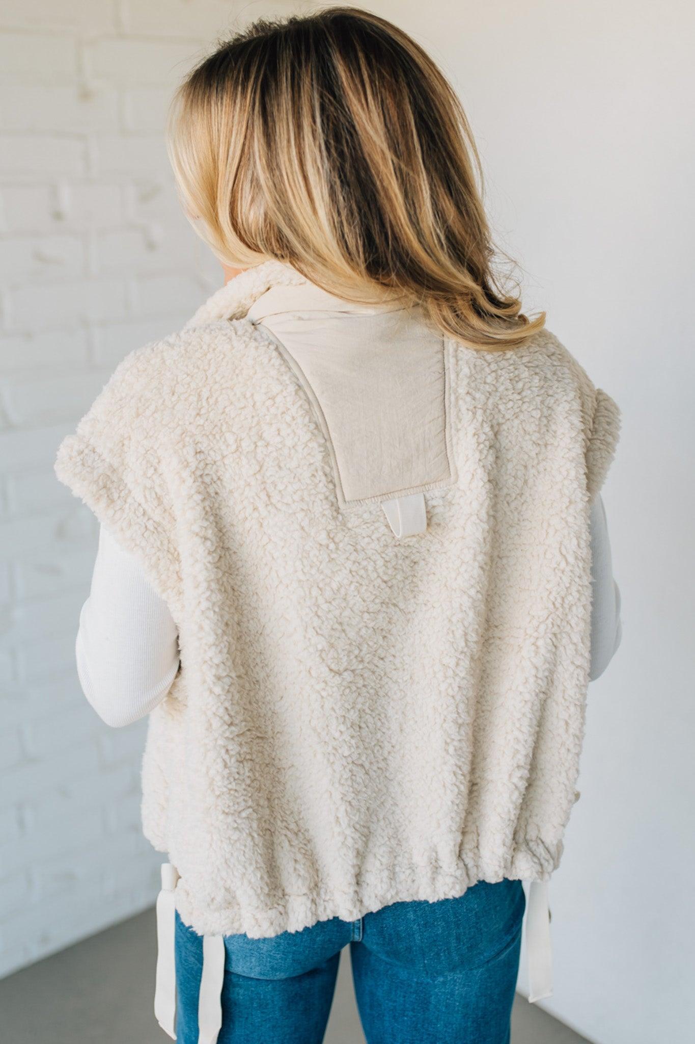 Person wearing a beige fleece vest with a white background