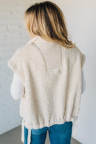 Person wearing a beige fleece vest with a white background