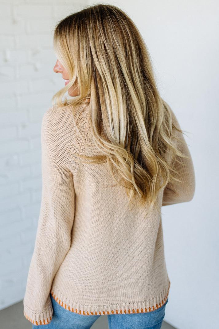Woman wearing a beige sweater with a white background