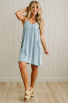 Woman wearing a light blue dress with a white wall background