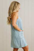 Woman wearing a light blue dress against a white paneled wall