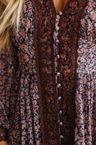 Close-up of a floral long-sleeve top with a dark brown lace front panel and silver buttons, worn by a model.