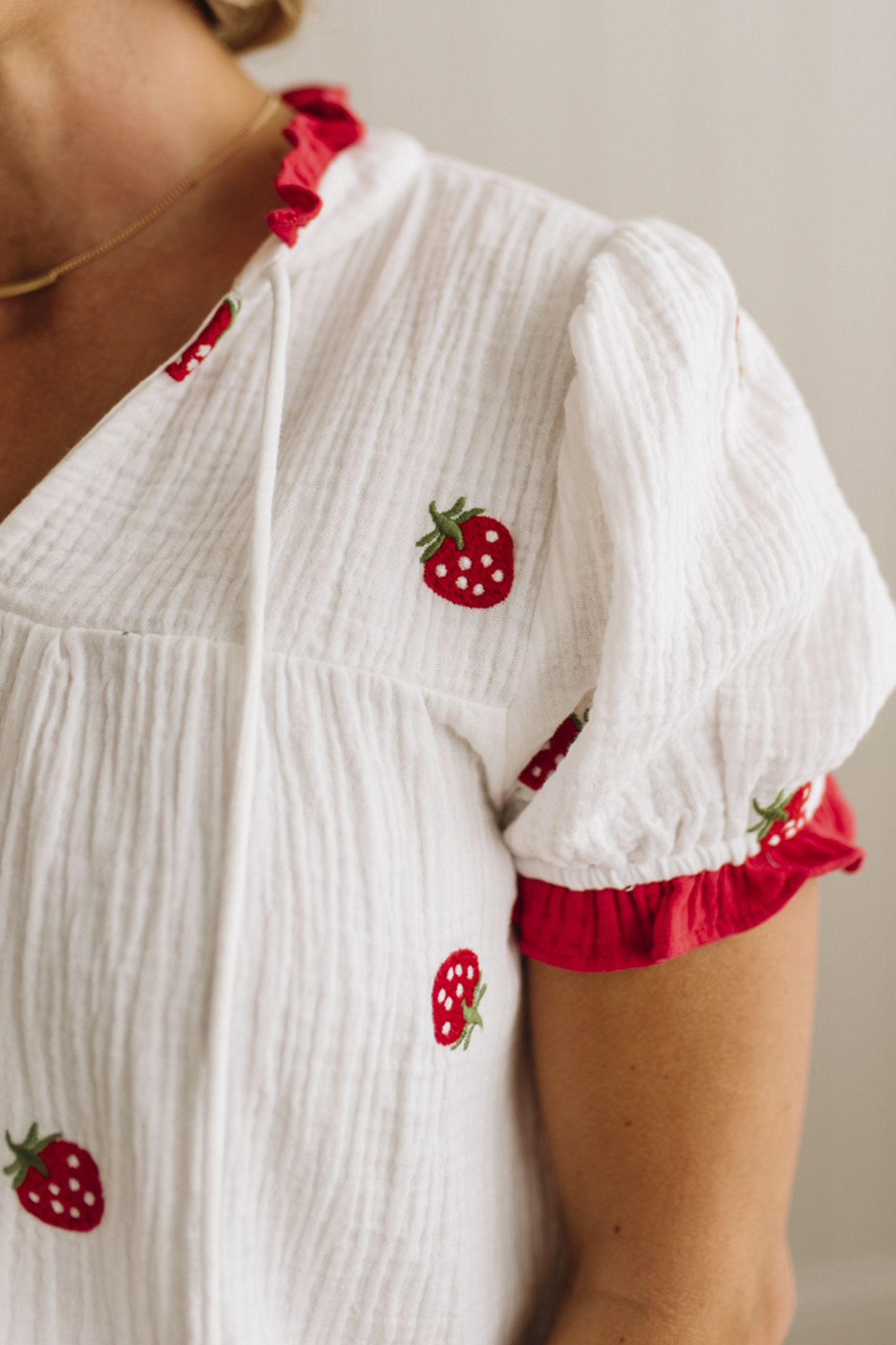 White blouse with red strawberry patterns on a neutral background