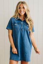 Woman wearing a blue denim dress against a light wooden panel background