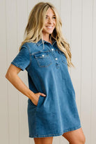 Woman wearing a denim dress against a light wooden panel background