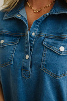 Close-up of a blue denim shirt with a gold necklace.