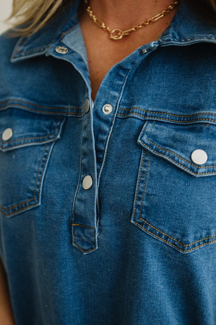 Close-up of a blue denim shirt with a gold necklace.