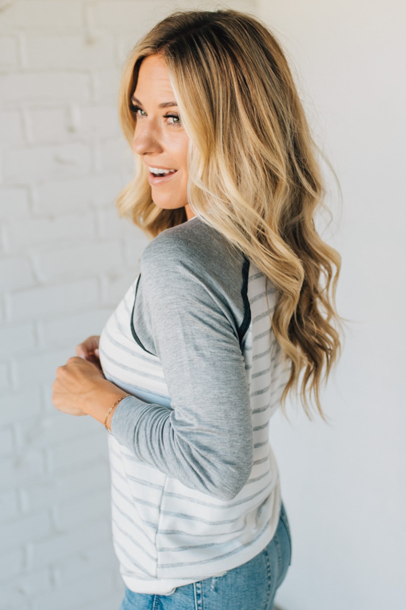 Woman wearing a gray and white striped long-sleeve shirt against a white background