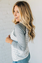 Woman wearing a gray and white striped long-sleeve shirt against a white background