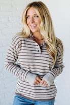 Woman wearing a striped sweater against a white brick wall