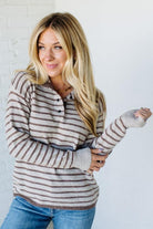 Woman wearing a striped sweater and jeans against a plain background