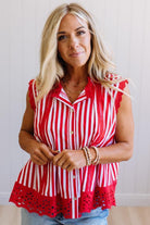 Woman wearing a red and white striped blouse with lace details on a plain background