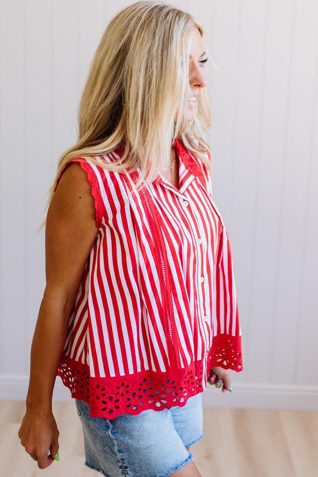 Woman wearing a red and white striped shirt with cut-out details on a plain background