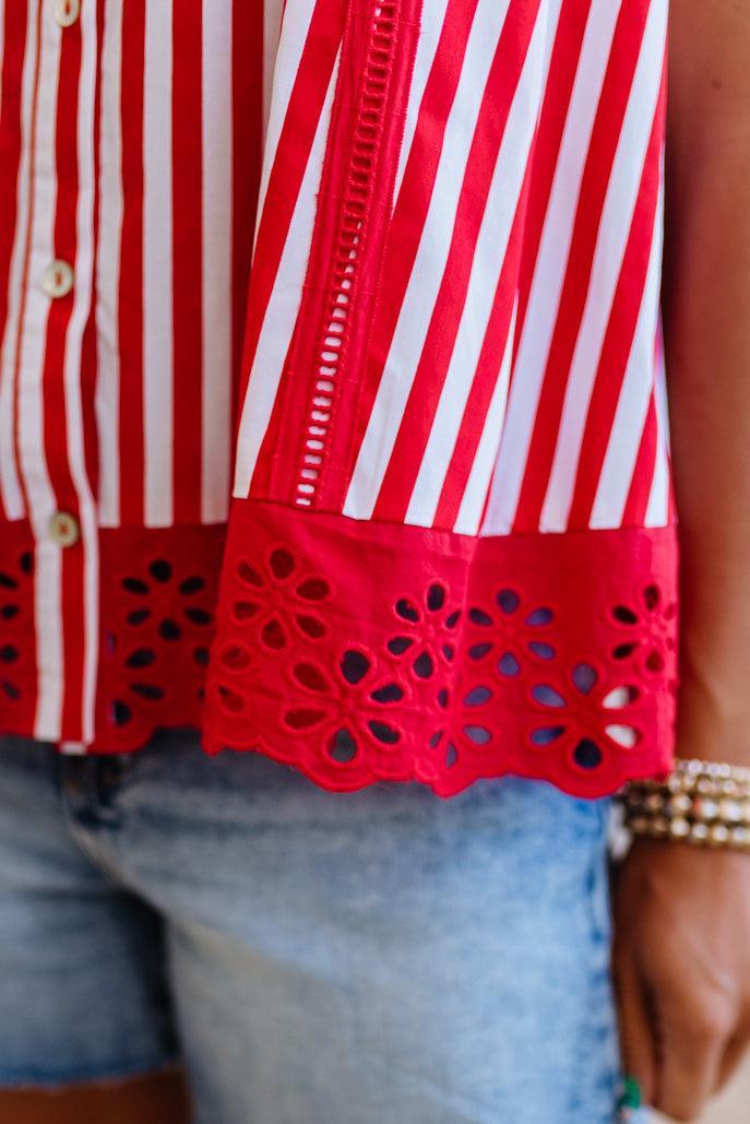 Red and white striped shirt with cut-out details on a person wearing jeans.