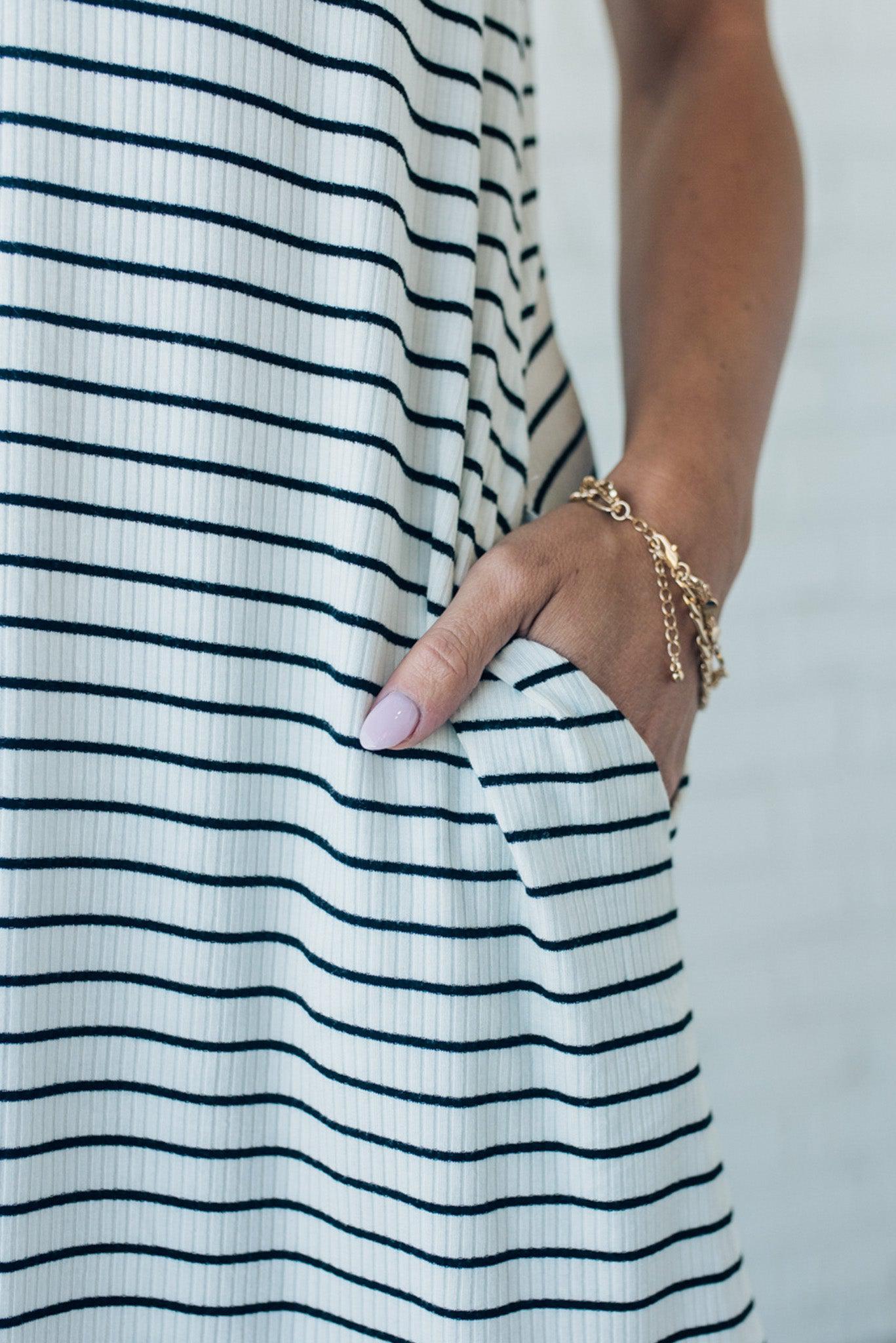 woman wearing a black and white striped tank dress that is knee length and has side pockets