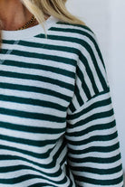 Green and white striped sweater worn by a person on a plain background