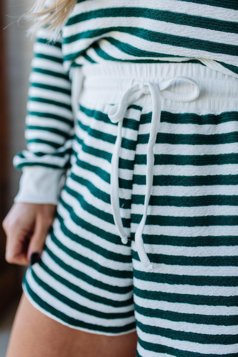 Green and white striped shorts with a drawstring on a blurred background