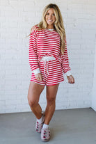 Woman wearing a red and white striped outfit against a white brick wall.