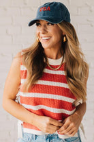 Blonde woman in a hat and shorts wearing a red striped sweater tank with double side ties.