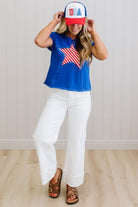 Person wearing a blue top with a red, white, and blue cap and pants indoors.