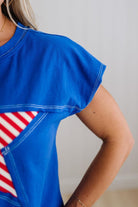 Blue top with red and white striped design worn by a person against a neutral background