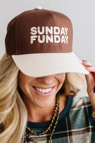 Blonde woman in a plaid green top wearing a hat that is brown with a cream brim, and cream bold lettering embroidered saying: SUNDAY FUNDAY