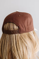 Blonde woman in a plaid green top wearing a hat that is brown with a cream brim, and cream bold lettering embroidered saying: SUNDAY FUNDAY