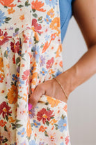 Person wearing a colorful floral overalls with a neutral background
