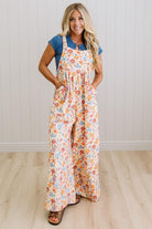 Woman wearing a floral overalls with a blue top indoors.