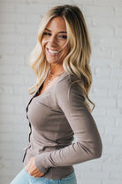 Woman wearing a brown cardigan against a white brick wall