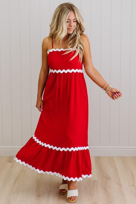 Woman wearing a red dress with white trim against a white wall.