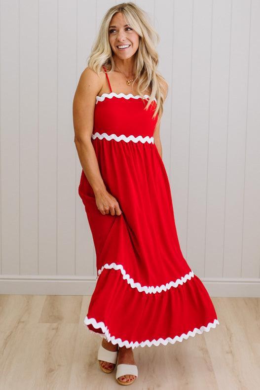 Woman wearing a red dress with white trim against a white wall.