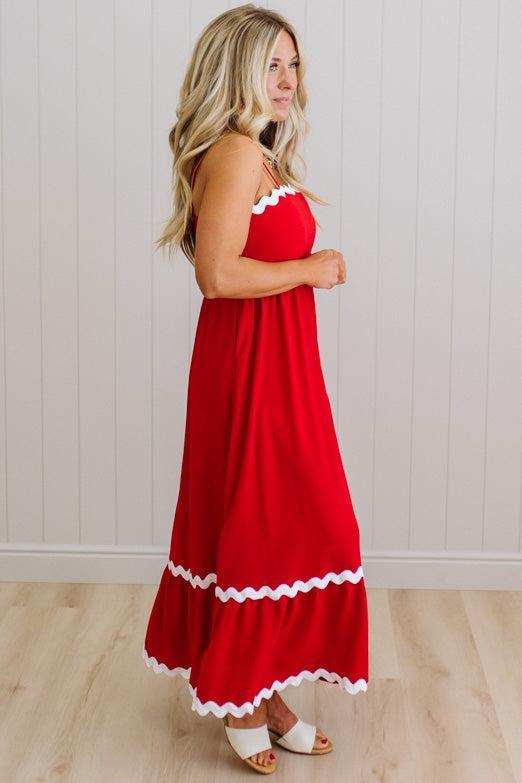 Woman wearing a red dress with white trim against a light wooden panel background
