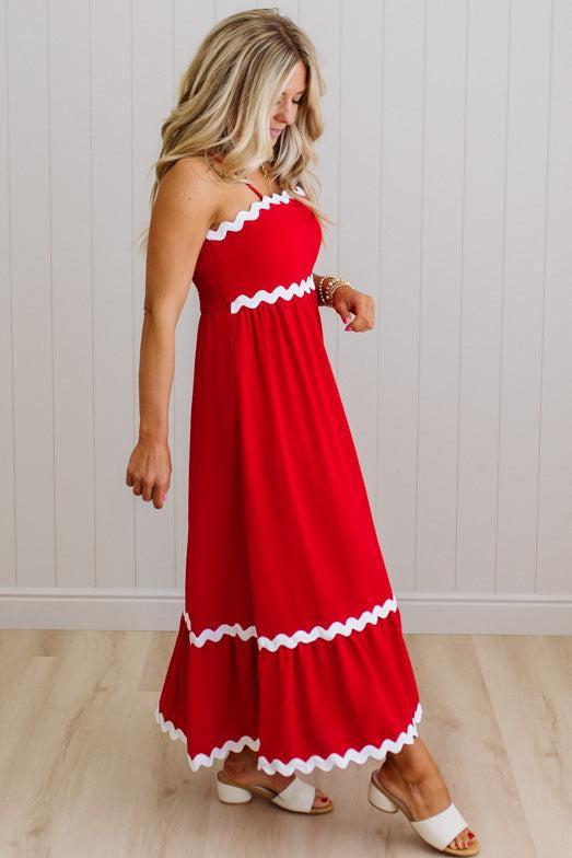 Woman wearing a red dress with white trim against a light wooden panel background
