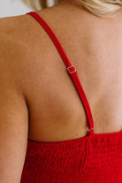 Red dress with thin straps and a visible buckle on a person's back.