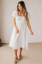 BLONDE WOMAN WEARING A WHITE, PUFF HALF SLEEVE, SQUARE NECKLINE, EYELET MIDI DRESS WITH TIE STRAP BACK.