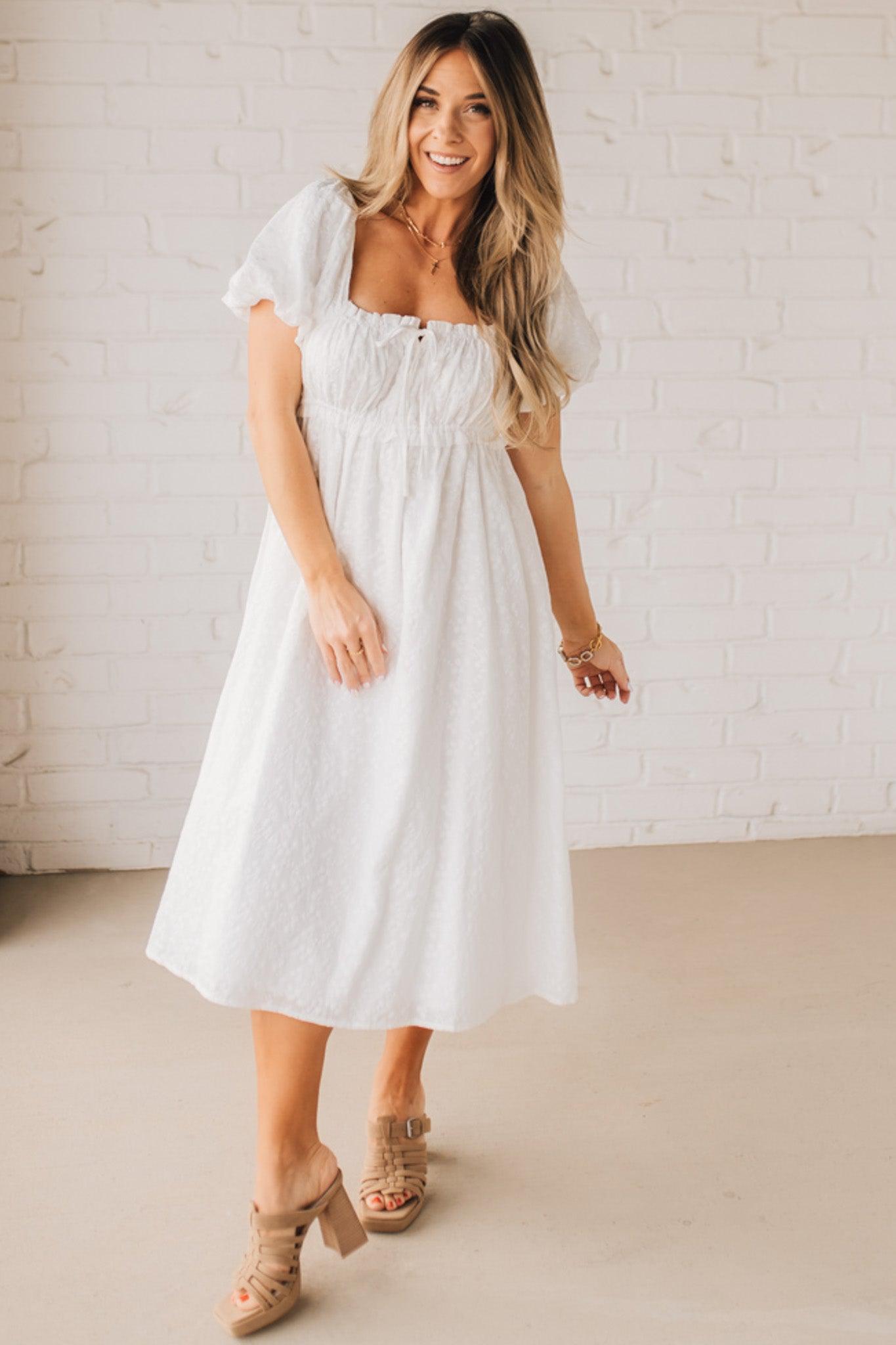 BLONDE WOMAN WEARING A WHITE, PUFF HALF SLEEVE, SQUARE NECKLINE, EYELET MIDI DRESS WITH TIE STRAP BACK.