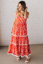 BLONDE WOMAN WEARING A RED FLORAL PRINT SLEEVELESS MAXI FEATURES: TIERED SKIRT PANEL WITH LACE INSET DETAIL, SMOCKED BACK, HIDDEN SIDE ZIPPER, THICK STRAPS WITH SCALLOPED LACE EDGES, SIDE POCKETS AND FULL LINING.