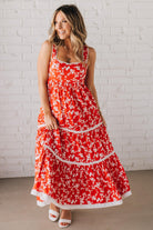 BLONDE WOMAN WEARING A RED FLORAL PRINT SLEEVELESS MAXI FEATURES: TIERED SKIRT PANEL WITH LACE INSET DETAIL, SMOCKED BACK, HIDDEN SIDE ZIPPER, THICK STRAPS WITH SCALLOPED LACE EDGES, SIDE POCKETS AND FULL LINING.