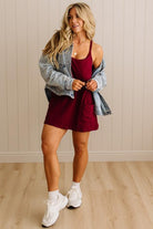 Woman wearing a red dress with a denim jacket indoors.