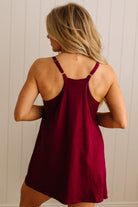 Woman wearing a burgundy slip dress against a neutral background