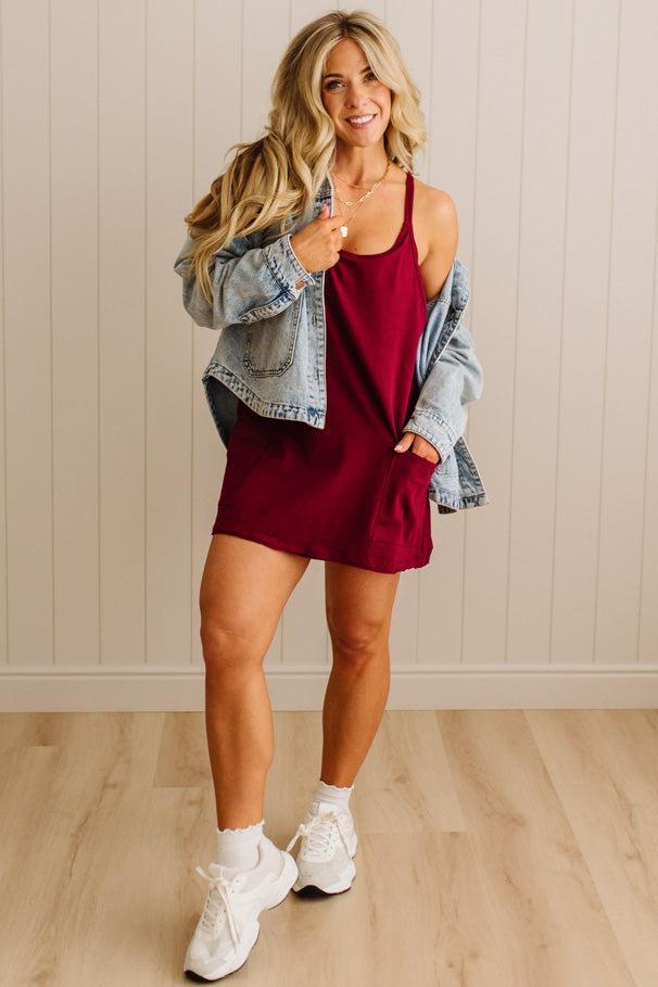 Woman wearing a red dress with a denim jacket indoors.